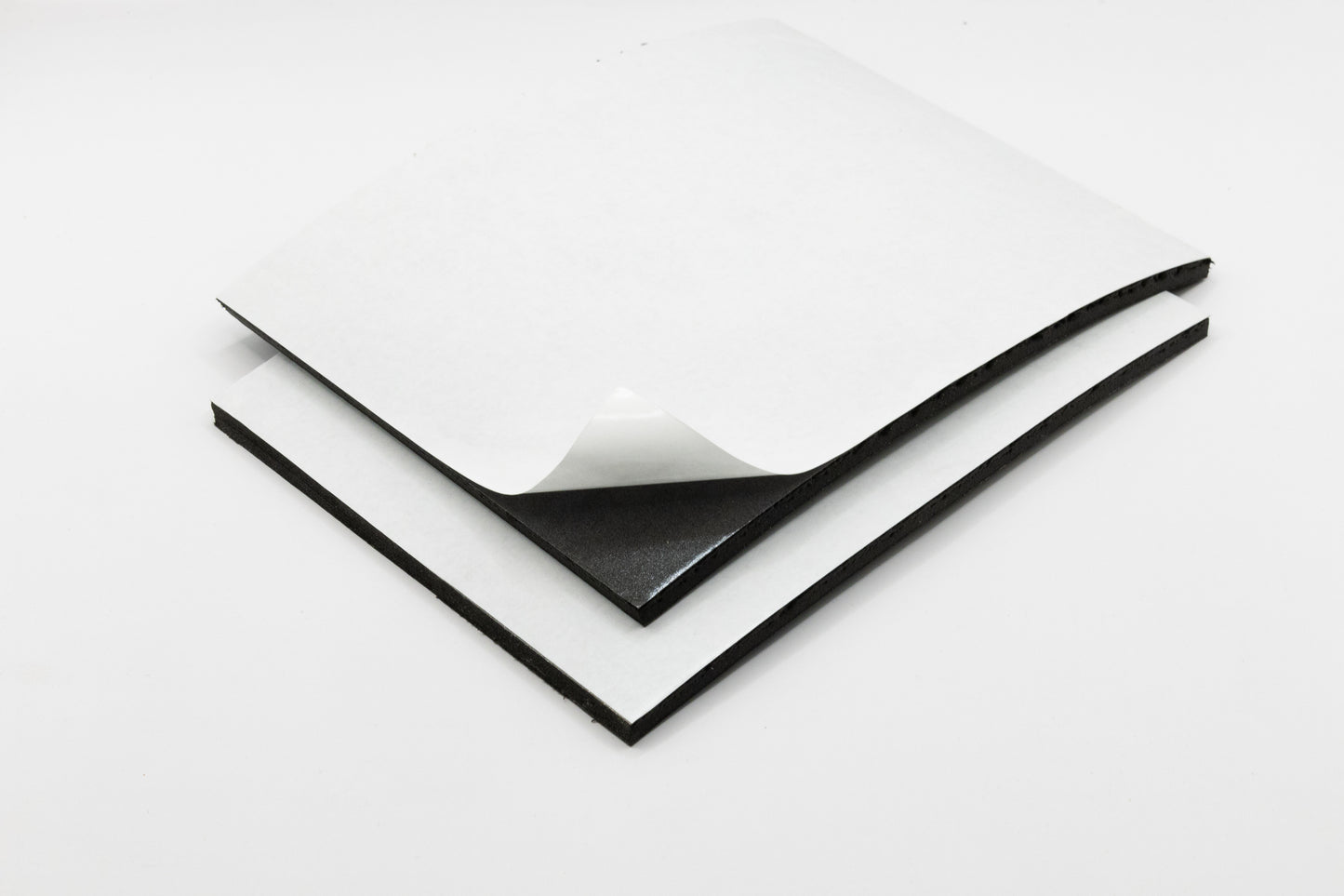 A piece of foam with adhesive backing peeling away from a sheet, showing the adhesive side.