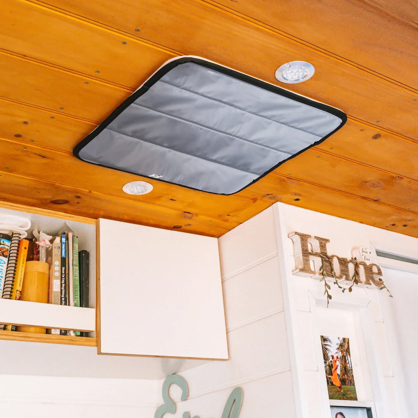 Ceiling-mounted storage bag on a wooden ceiling with books and decor below.