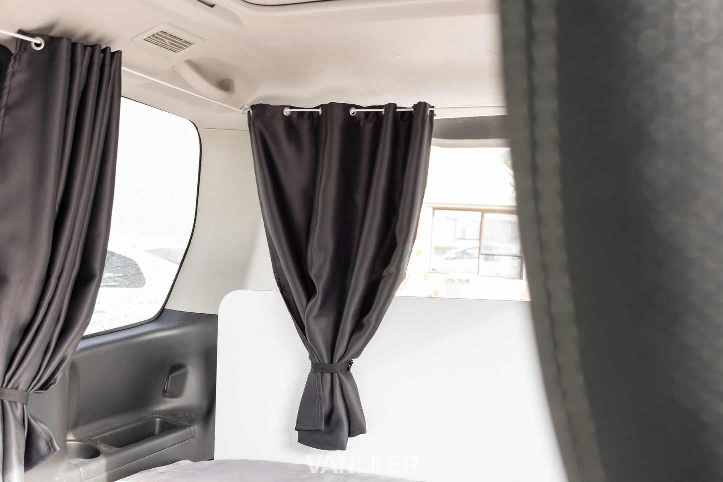 Black curtains hanging inside a vehicle with a blurred background