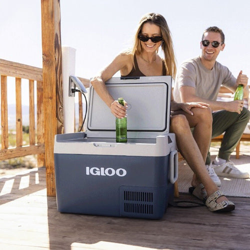 Couple enjoying drinks from the Igloo ICF18 Portable Fridge/Freezer on a deck, showcasing its convenience and portability.