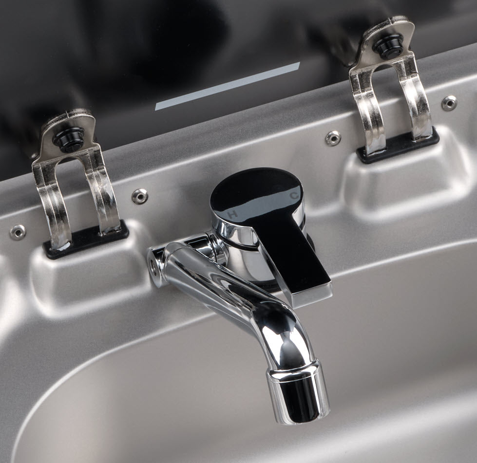 Close-up of a metallic faucet with two handles on a sink.