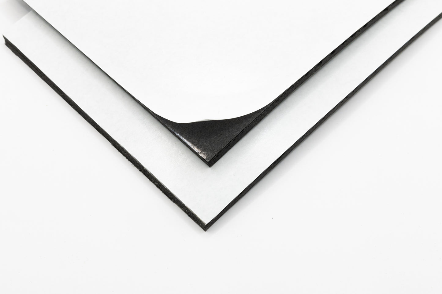 A piece of foam with adhesive backing peeling away from a sheet, showing the adhesive side.