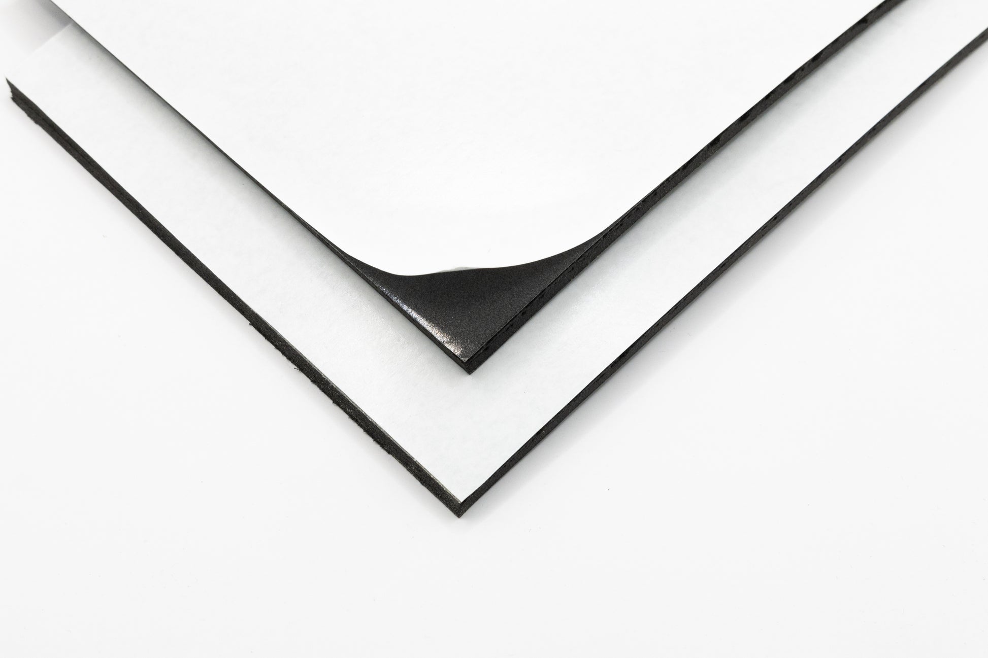 A piece of foam with adhesive backing peeling away from a sheet, showing the adhesive side.