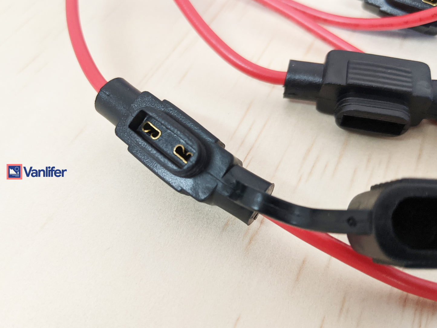 Close-up of  connectors with red and black cables on a light background, featuring the Vanlifer brand.