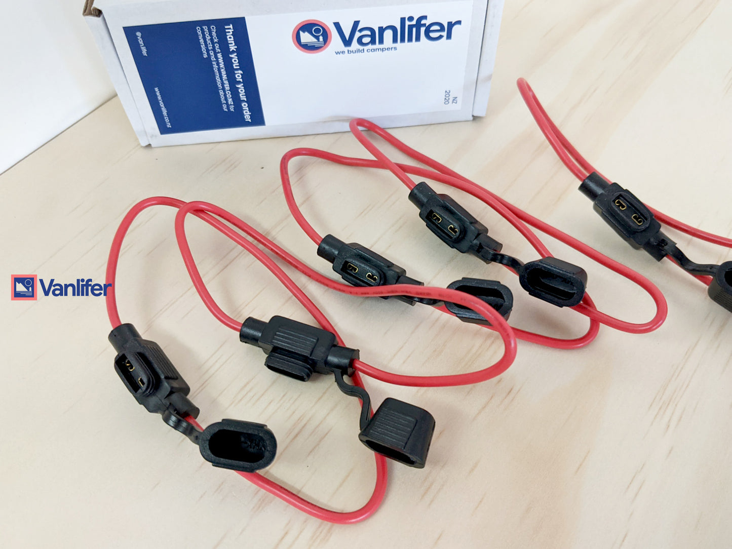 Red and black electrical connectors with Vanifer branding on a light wooden surface.