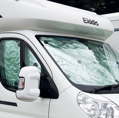 A thermal blind set installed on the interior of a white motorhome, designed to regulate temperature and reduce light seepage.