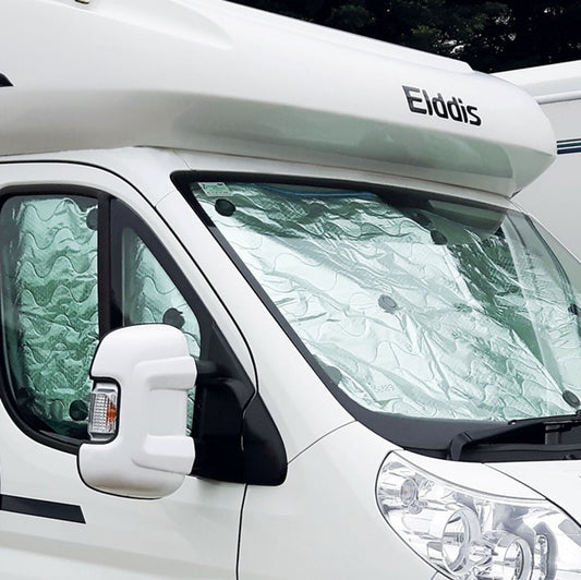 A thermal blind set installed on the interior of a white motorhome, designed to regulate temperature and reduce light seepage.