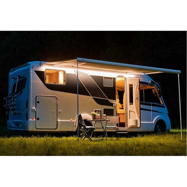 RV with an extended awning at night on a grassy area