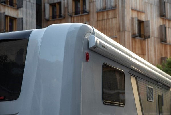 Roof of a vehicle with a window and light, parked in front of a building.