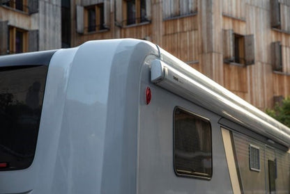 Roof of a vehicle with a window and light, parked in front of a building.