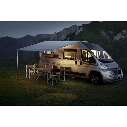 Camper van with an extended awning in a mountainous area at night