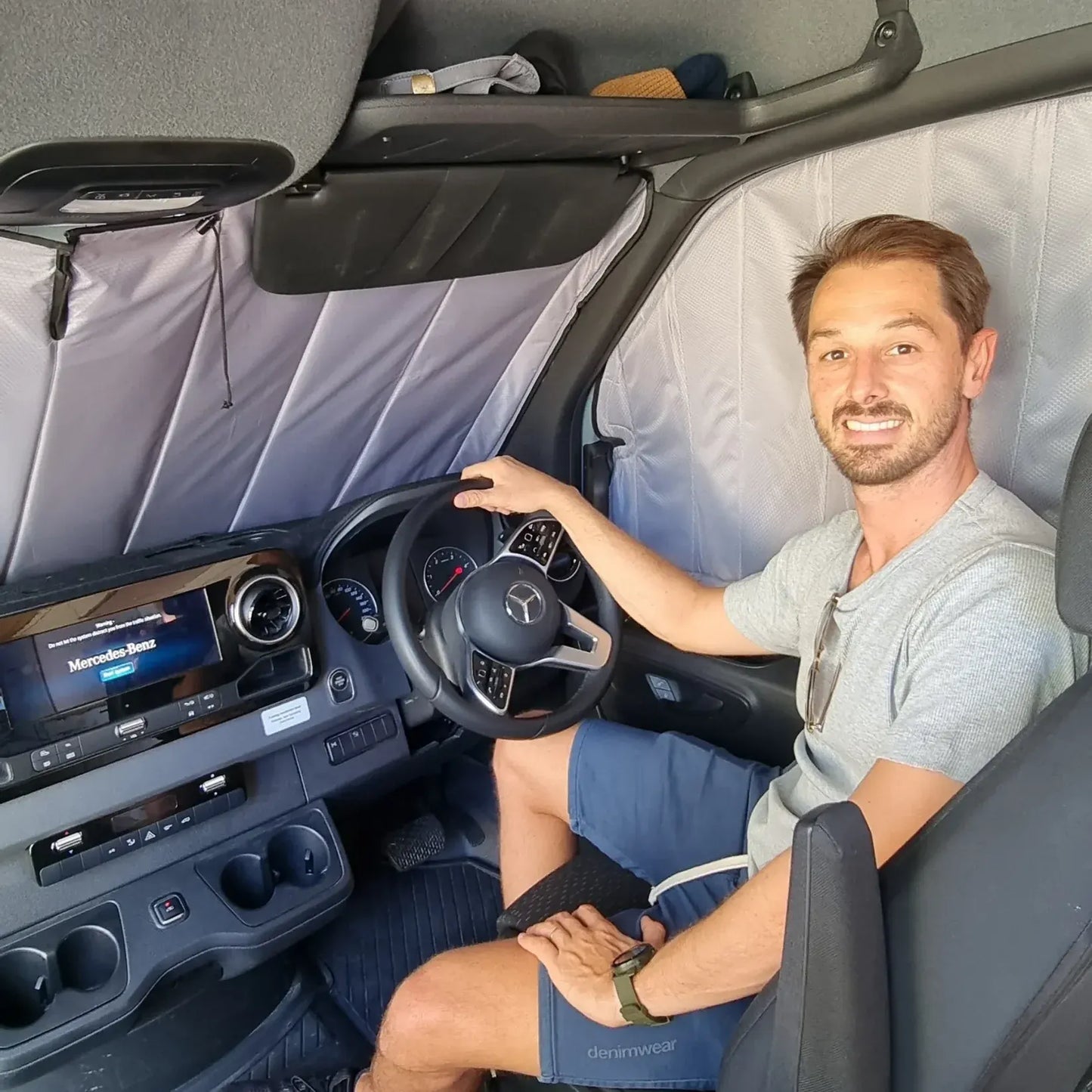 Window covers providing privacy for a man sitting inside a van with a Mercedes-Benz logo on the dashboard