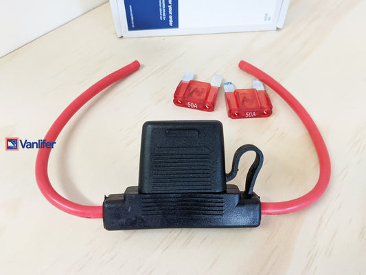 Black electrical connector with red wires and fuses on a light wooden surface, Vanlifer brand visible.