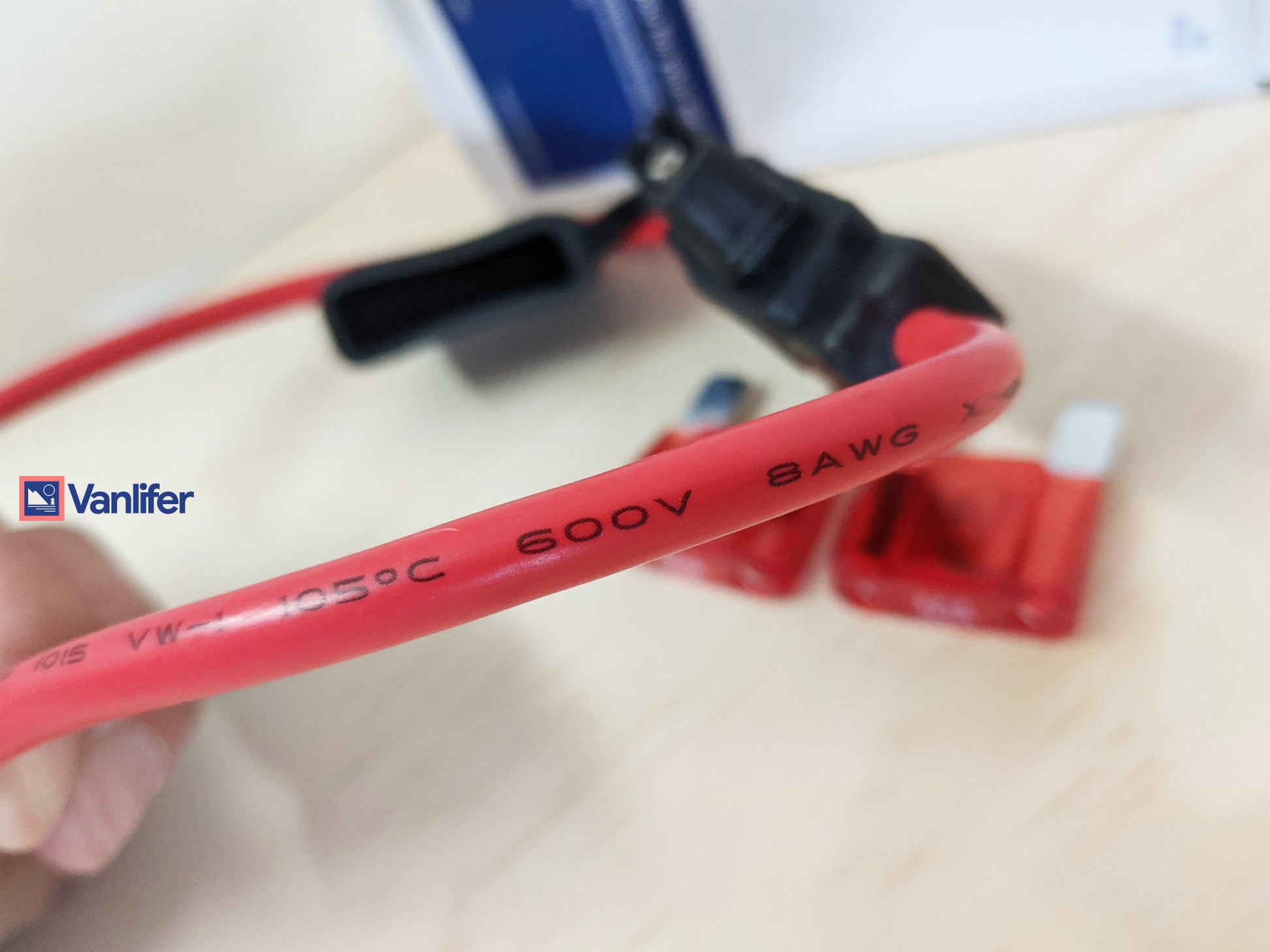 Red electrical cable with Vanlifer branding held by a hand on a blurred background