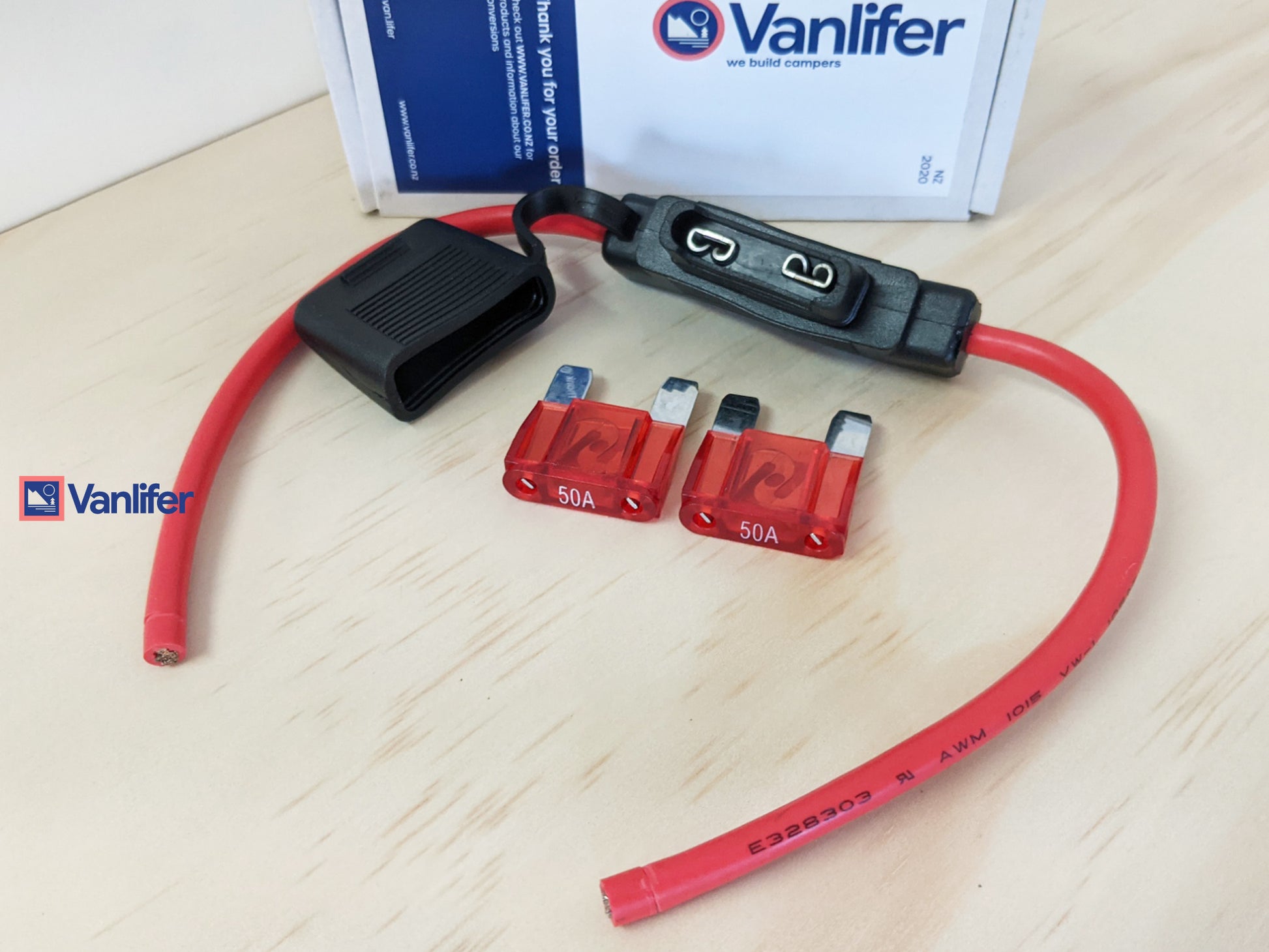 Vanlifer fuse box with red wires and fuses on a light wooden surface