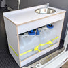 A white plastic sink installed on a wooden cabinet with water tanks below, secured with yellow straps
